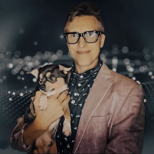 Carey Balboa, founder of IT Help San Diego, in glasses and a blazer holding his companion, against a dark bokeh background.
